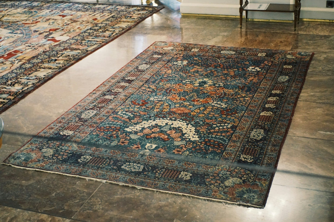 Hand-knotted Persian rug with an ornate medallion design displayed on a polished wood floor